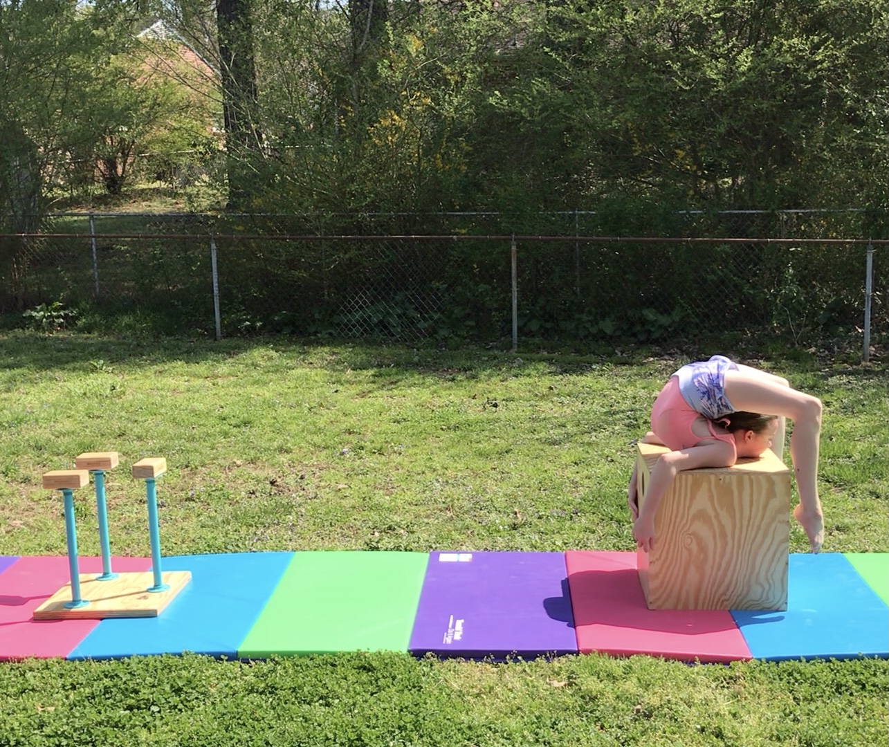Jocelyn performs a backbend on a cube that is part of her outdoor stage