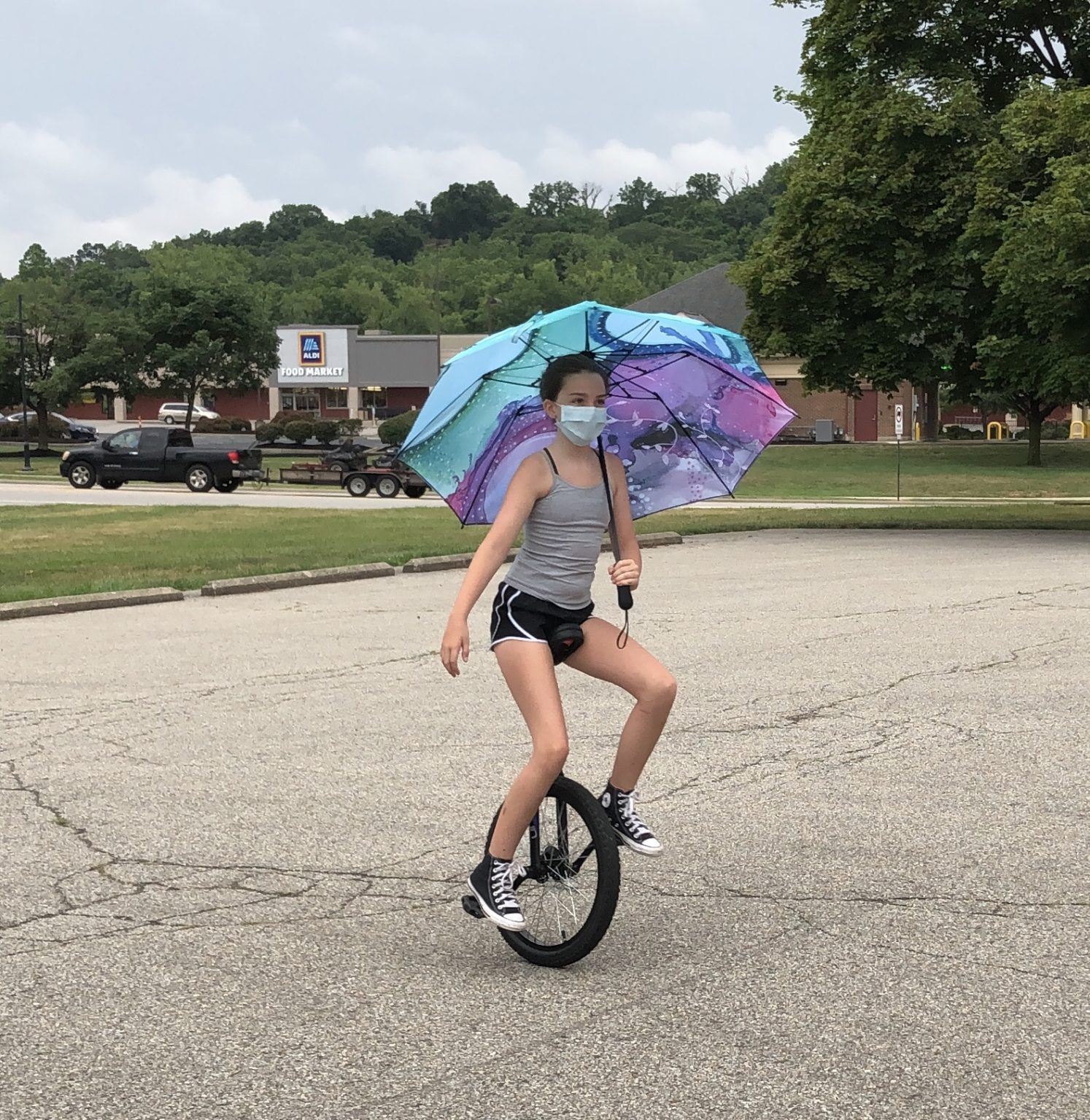 my nose turns red youth circus performer unicycling with an umbrella while wearing a mask